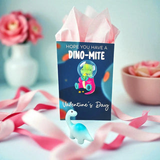 Valentine's Day gift box with dinosaur design and pink ribbons on a light background