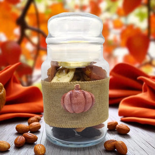 Glass jar with a decorative pumpkin label on a wooden surface with autumn-themed background