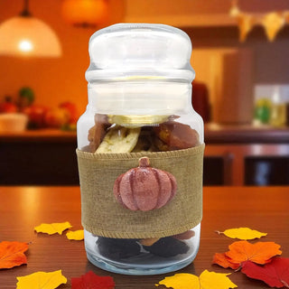 Glass jar with a pumpkin-themed label on a wooden surface with autumn leaves