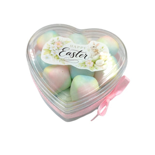 Heart-shaped container with pastel Easter eggs and a 'Happy Easter' card on a white background