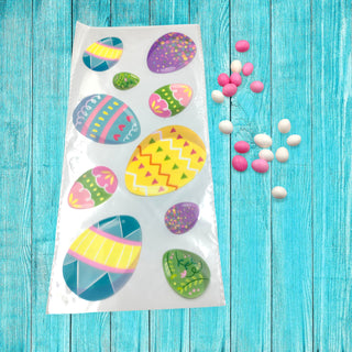 Packaged Easter egg stickers on a blue wooden surface with small candy eggs.