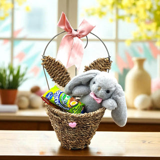 Easter basket with plush bunny, candy, and decorative elements on a table.