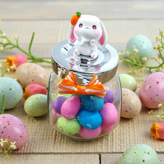 Decorative jar with colorful Easter eggs and a bunny figurine on top, surrounded by Easter-themed decorations.