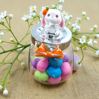 Glass jar with colorful candies and a rabbit-shaped lid on a textured surface with flowers.