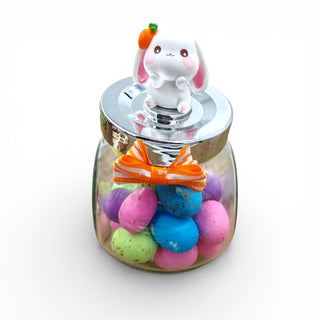 Glass jar with colorful balls and a cute rabbit figurine on a white background