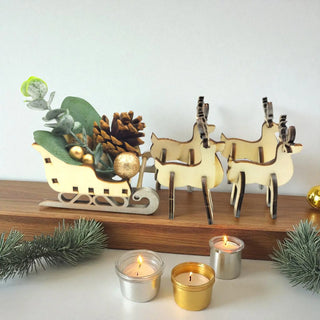 Decorative wooden reindeer and sleigh with candles on a white surface