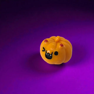 Yellow pumpkin-shaped toy with a face on a purple background