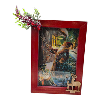 Decorative Christmas picture with a red frame, featuring a winter scene with a man and deer.