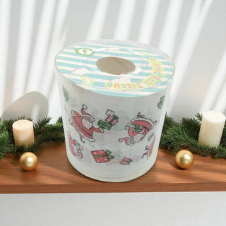 Tissue paper roll with Christmas design on a wooden surface with candles and gold balls.