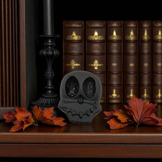 Gray skull-shaped object on a wooden surface with autumn leaves and books in the background
