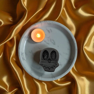 Candle with skull design on a gold fabric background