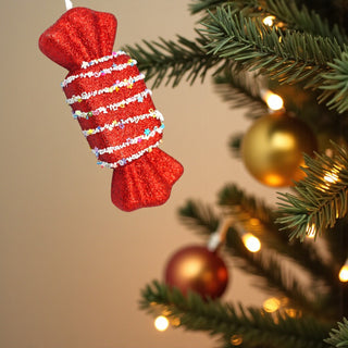 Confetti nougat candy ornament on frosted pine tree with warm fairy lights. red Candyland Christmas decorating inspiration