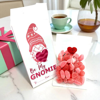 Greeting card with gnome design and candy on a table with a gift and tea.