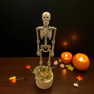 Skeleton figure in a pot with pumpkins and candles on a dark background