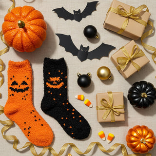 Halloween-themed socks with pumpkins, bats, and gift boxes on a neutral background