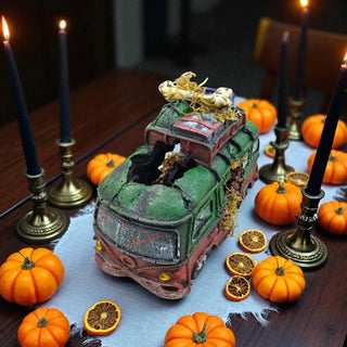 Decorative Halloween scene with a model train, pumpkins, and candles on a table.