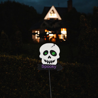white skull with green eyes above sign written "spooky" in purple