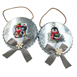 Two Christmas ornaments with penguins and ribbons on a white background
