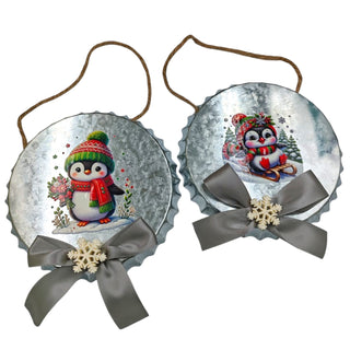 Two Christmas ornaments with penguins and ribbons on a white background