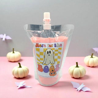Pink pouch with a ghost design labeled 'Here for the Boas' on a pink surface with small pumpkins.