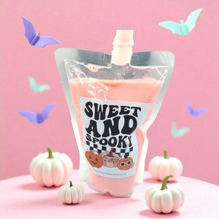 Pink pouch with 'Sweet and Spooky' label on a pink background with pumpkins and butterflies.