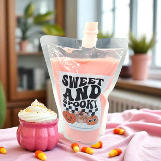 Pink IV bag in a pumpkin-shaped container with a 'Sweet and Spooky' labeled pouch on a pink surface.