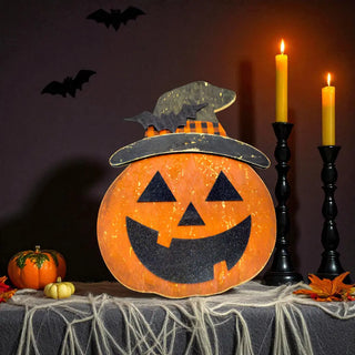 Halloween-themed decoration with a jack-o'-lantern, candles, and pumpkins on a dark background.