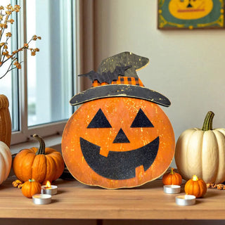 Decorative pumpkin with a witch hat on a table with other pumpkins and candles.