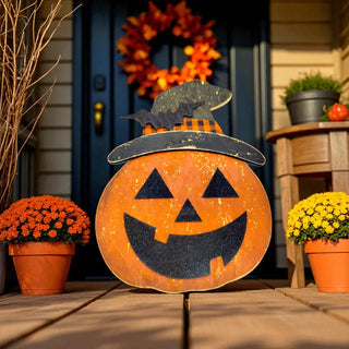Decorative pumpkin with witch hat on a porch with potted plants and a wreath.
