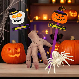 Halloween-themed decorations including a hand, spider, and pumpkins on a table.