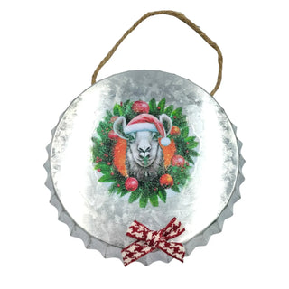 Decorative metal ornament with a sheep wearing a Santa hat and surrounded by Christmas wreath and decorations on a white background.