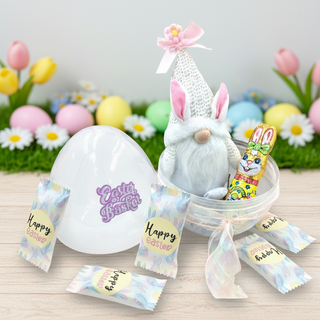 Easter-themed gift set with a plush bunny, candy, and decorative eggs on a wooden surface.