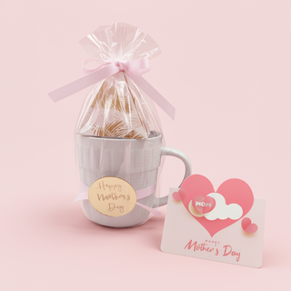 Gift set with a mug, wrapped product, and Mother's Day card on a pink background