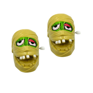 Toy mummy heads with green eyes and white teeth on a white background