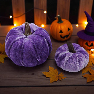 Purple velvet pumpkins on a wooden surface with Halloween decorations.