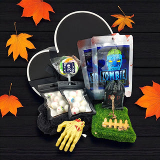Halloween-themed items including a zombie hand, candy, and decorative elements on a dark surface with orange leaves.