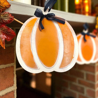 Decorative pumpkin ornament with a black bow on a brick wall background