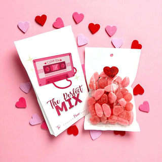 Cassette tape-themed card and heart-shaped candy on a pink background with heart decorations.
