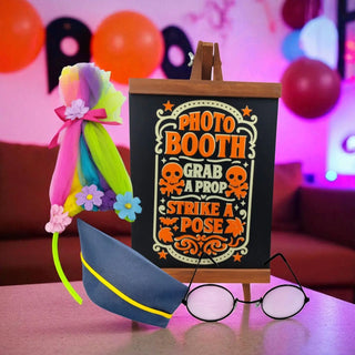 Photo booth sign with props on a table in a festive setting with balloons.