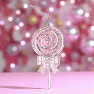 Decorative pink lollipop ornament with a bow on a blurred festive background