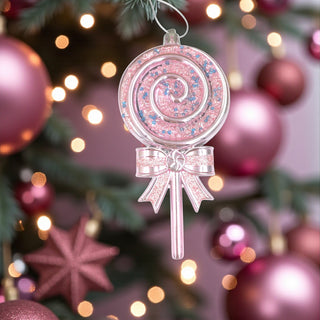 Pink lollipop ornament with a bow on a Christmas tree with pink and gold ornaments.