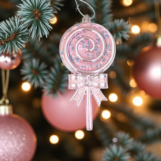 Pink lollipop ornament on a Christmas tree with lights and decorations.