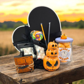 black heart shaped box. orange ceramic pumpkin stack, wooden pumpkin, lollipop, 2 candy eye packets, 2 halloween themed candy straws and a Halloween themed jar filled with candy