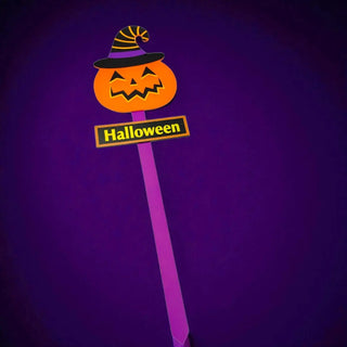 Halloween-themed decorative stick with pumpkin face and 'Halloween' sign on a purple background