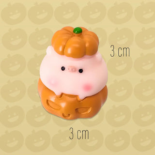 Small plush toy with a pumpkin on top on a beige background with pumpkin patterns.