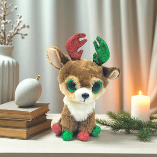 Plush reindeer toy with festive antlers on a table with books and a candle in the background