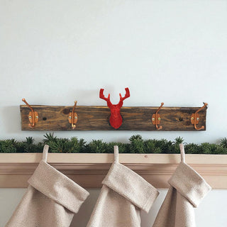 Wooden coat rack with deer head design above hanging stockings against a white wall.