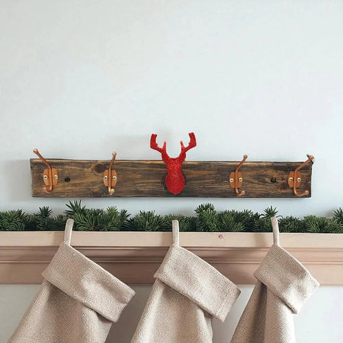 Wooden coat rack with deer head design above hanging stockings against a white wall.