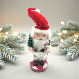 Decorative Santa Claus figure with a red hat and white beard, surrounded by Christmas tree branches and lights.