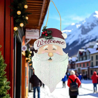 Decorative Santa Claus sign with 'Welcome' text in a snowy mountain village setting.